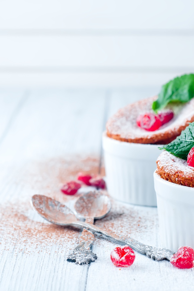 Пирожное с ягодами и сахарной пудрой на столе с ложками