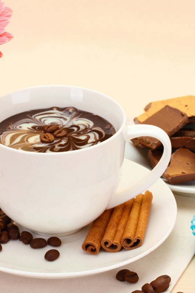 Конфеты на столе с кофе и герберой в вазе 