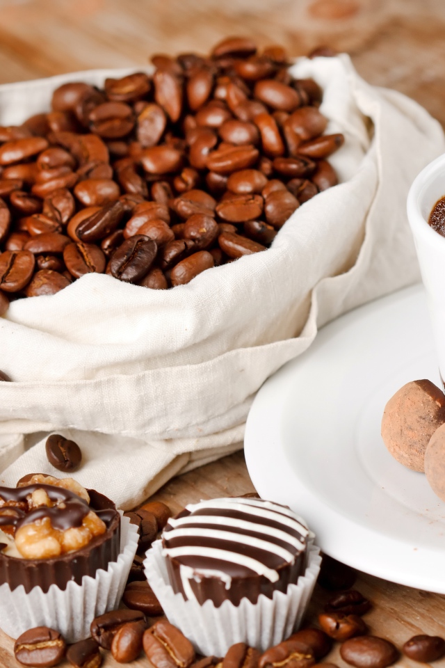 Шоколадные конфеты на столе с чашкой кофе и мешком с кофейными зернами