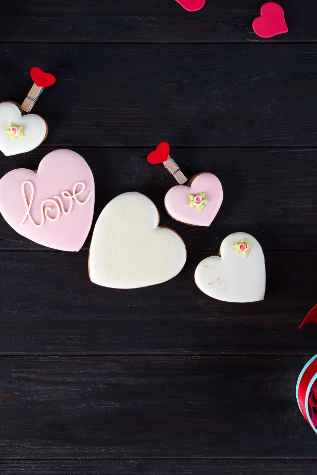 Печенье с глазурью на черной поверхности с сердечками и подарком