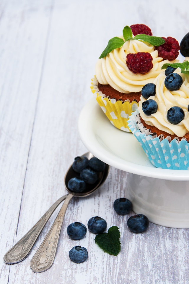 Кексы с кремом на белом блюде с ягодами