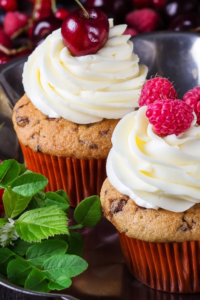 Аппетитные кексы с кремом и ягодами на блюде