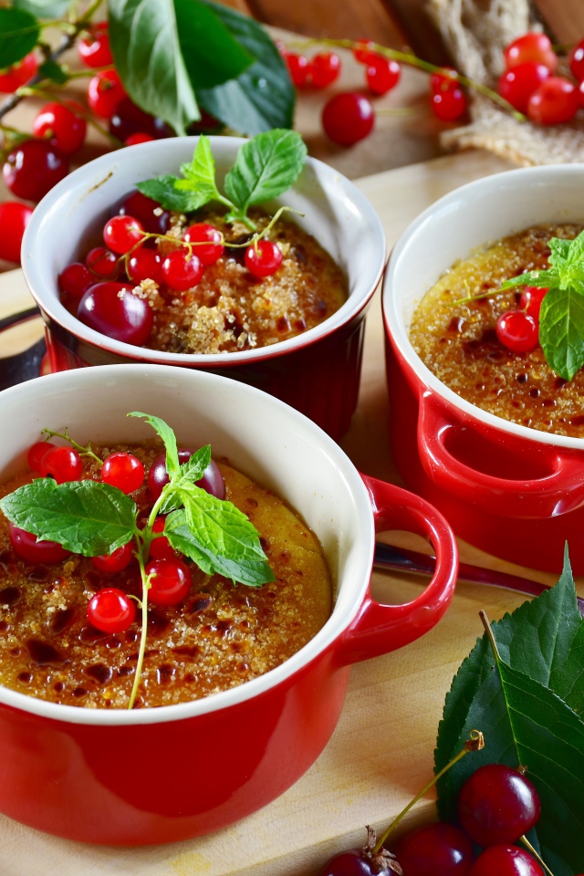 Десерт в красной посуде на столе с вишней и красной смородиной