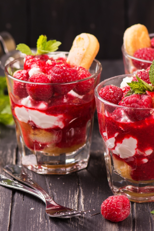 Десерт с печеньем и малиной на столе с вилками