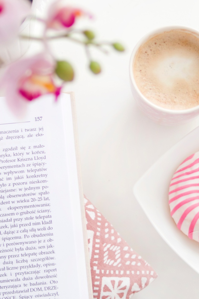 Donut with a cup of coffee on the table with a book
