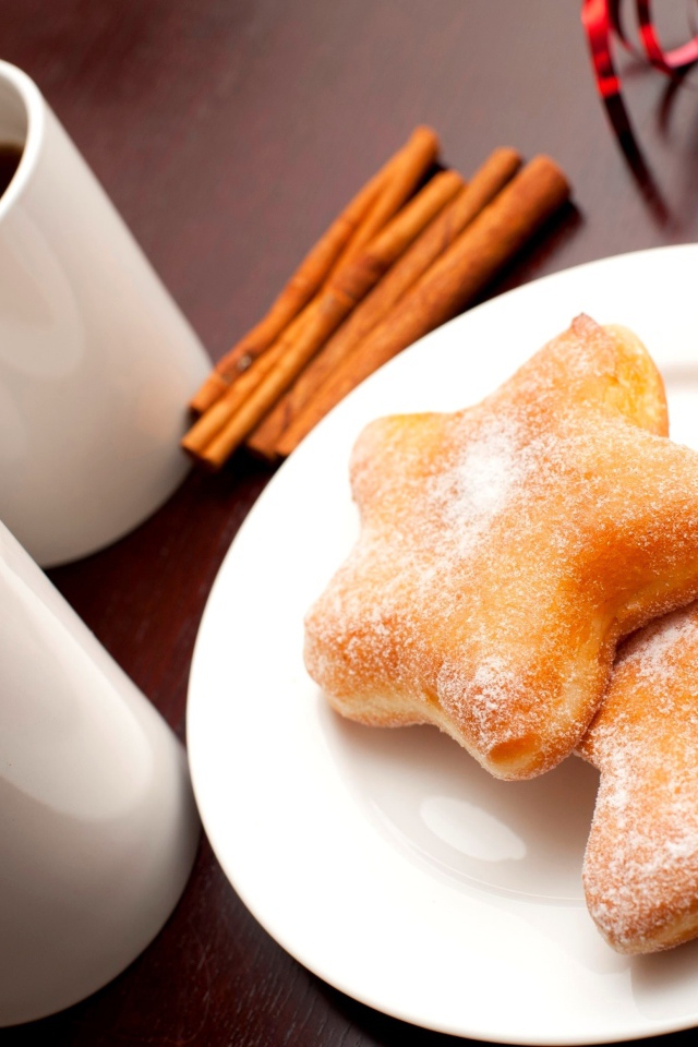 Пончики на столе с кофе и палочками корицы