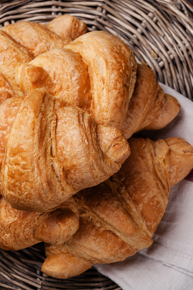 Свежие круассаны в корзинке с полотенцем