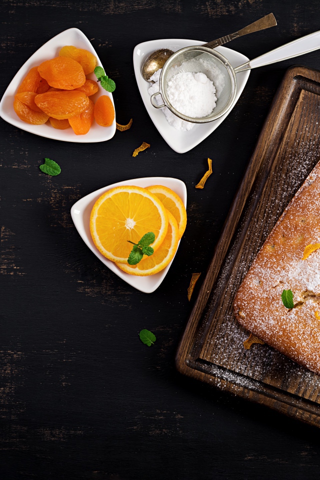 Свежий сладкий пирог на столе с курагой и апельсином