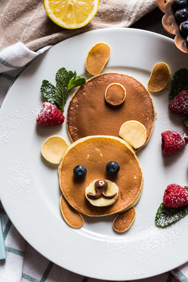 Медведь из оладьев на тарелке с малиной и сахарной пудрой