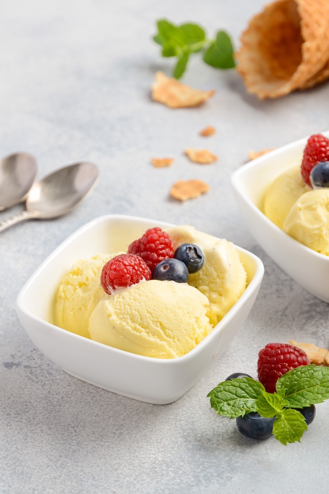 Шарики мороженого с ягодами на столе с вафельными рожками