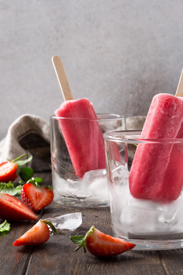 Фруктовое мороженое в стакане со льдом на столе с клубникой