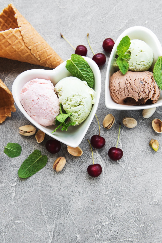 Мороженое на столе с вафельными рожками, шоколадом, вишней  и фисташками