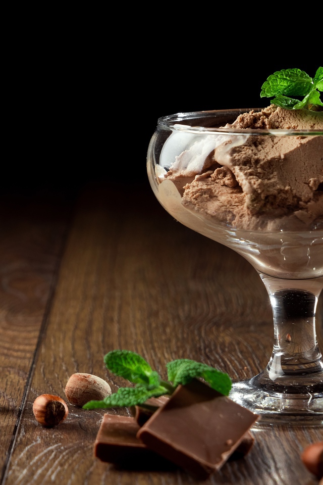 Кофейное мороженое в креманке на столе с шоколадом и орехами