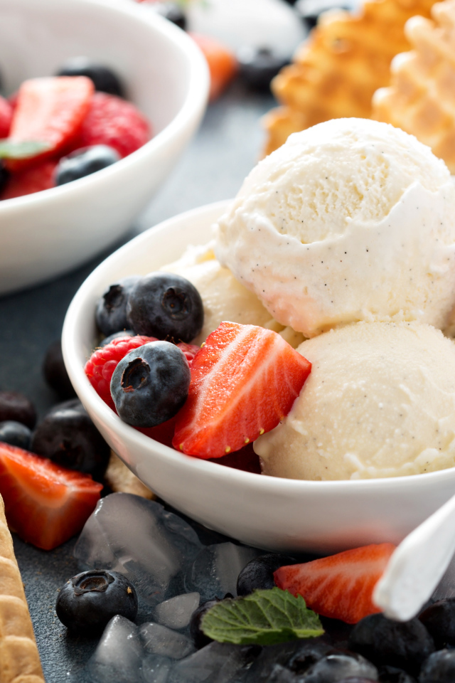 Мороженое с ягодами черники и клубники на столе с вафельными рожками