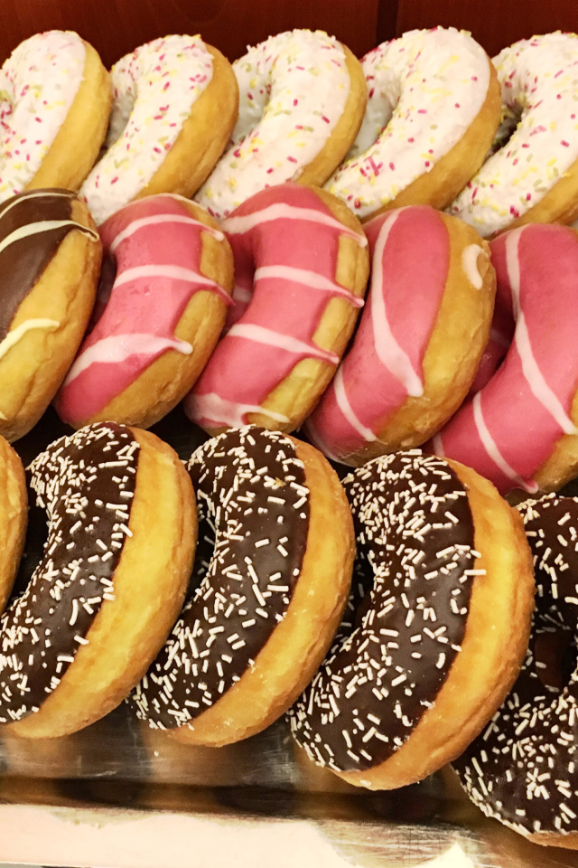 Много вкусных сладких пончиков с глазурью на столе 