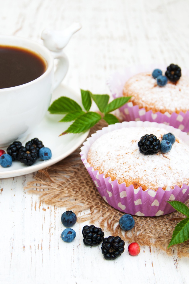 Кексы с сахарной пудрой и ягодами на столе с какао