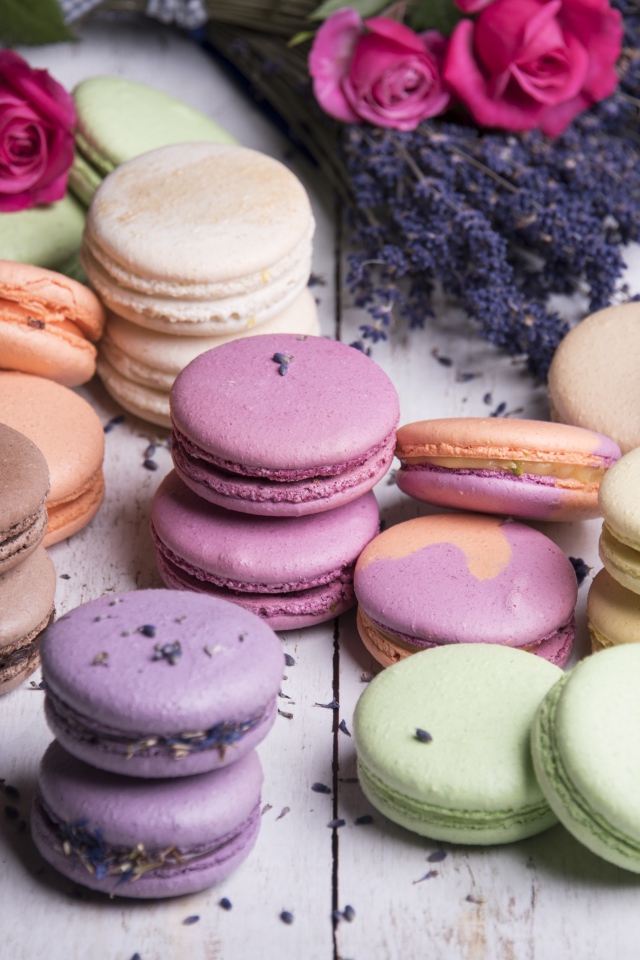 Разноцветный десерт макарон на столе с лавандой и розами