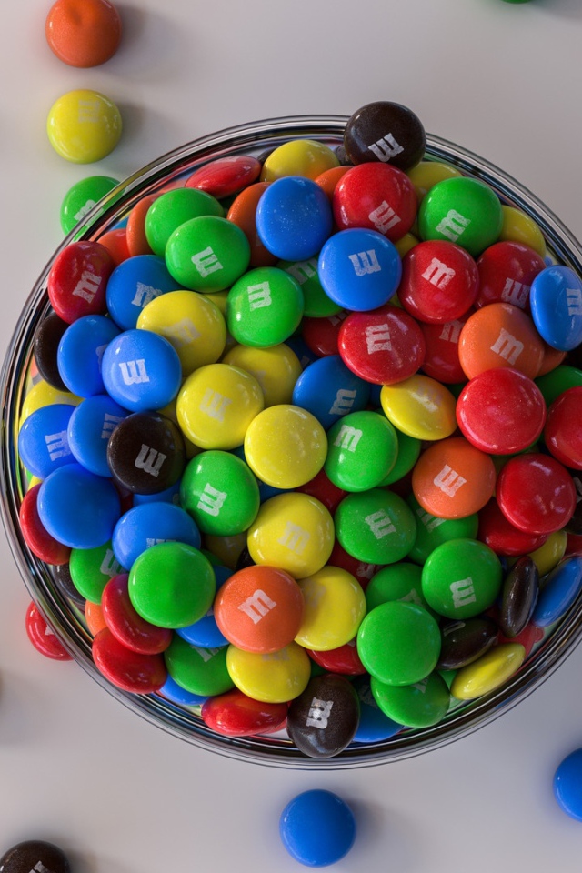 Разноцветные конфеты с миске на сером столе