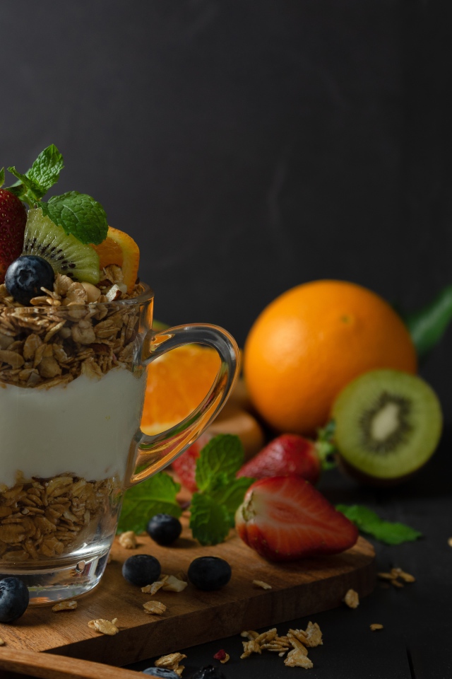 Овсяные хлопья с чашке с йогуртом на столе с ягодами и фруктами