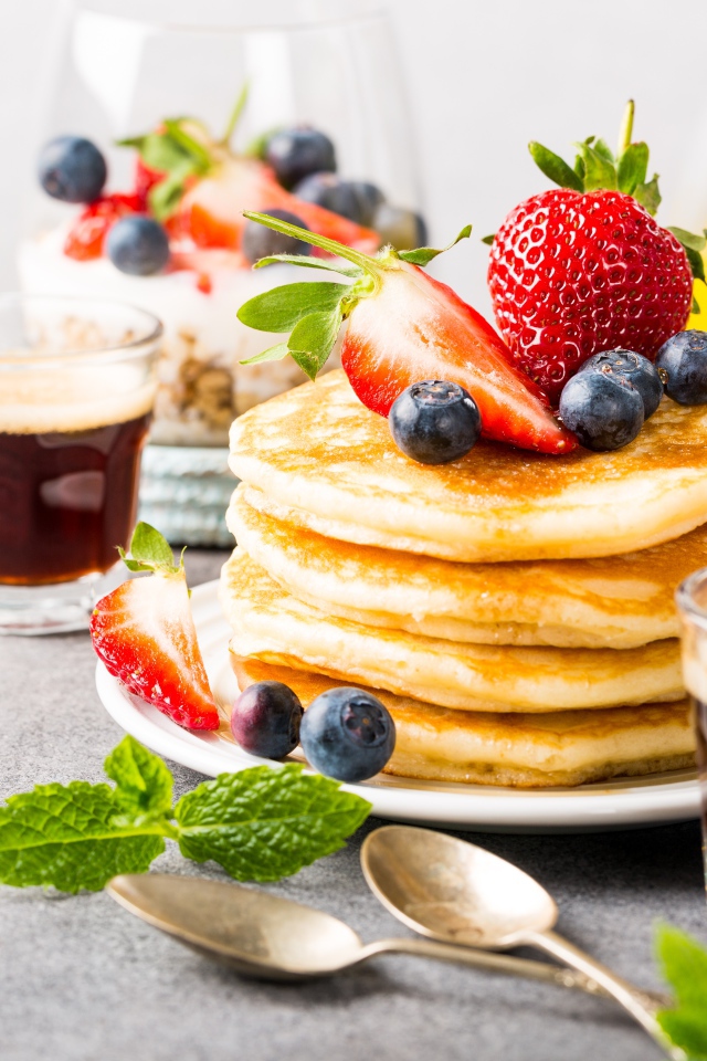 Оладьи с ягодами на столе с соком