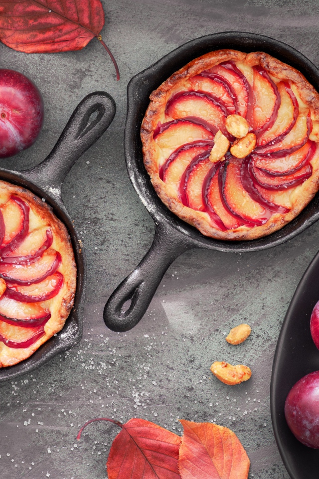 Пирог на столе с розовыми крупными сливами