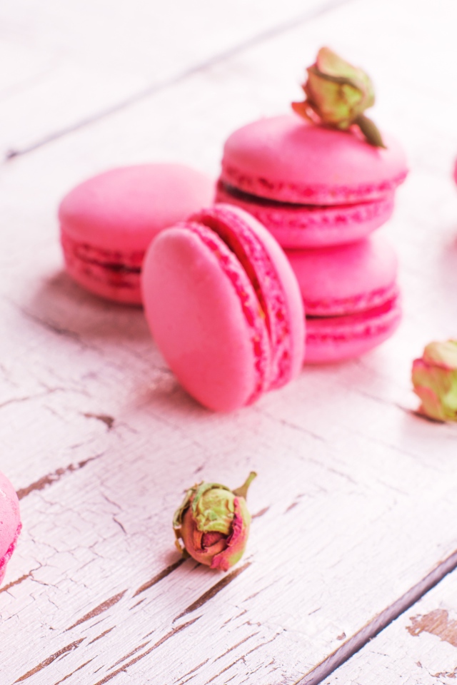 Розовый десерт макарон на столе с сухими розами