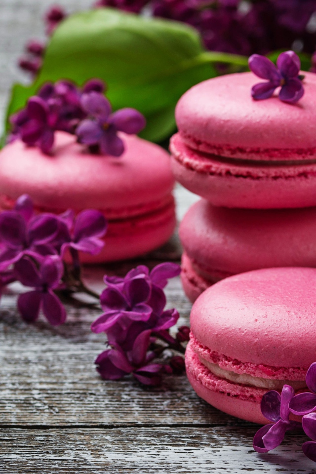 Розовый десерт макарон на столе с сиренью