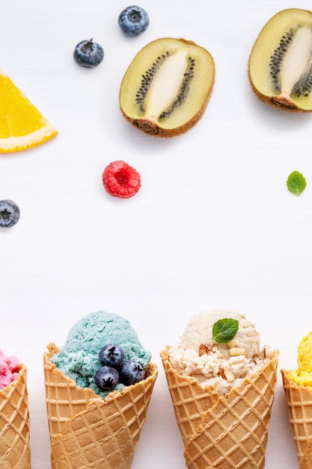Popsicles in waffle cones on a white plate with berries
