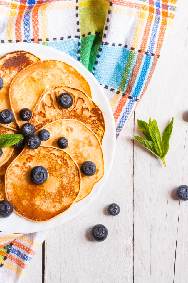 Румяные оладьи на тарелке с ягодами черники