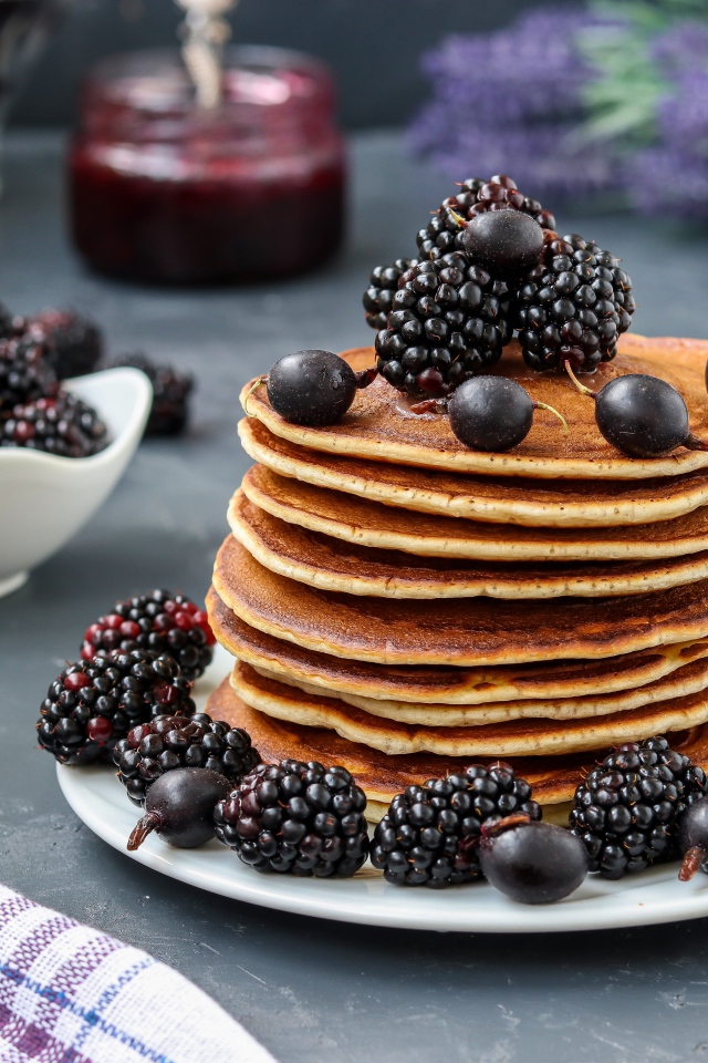 Румяные оладьи на тарелке с ягодами черники и смородины