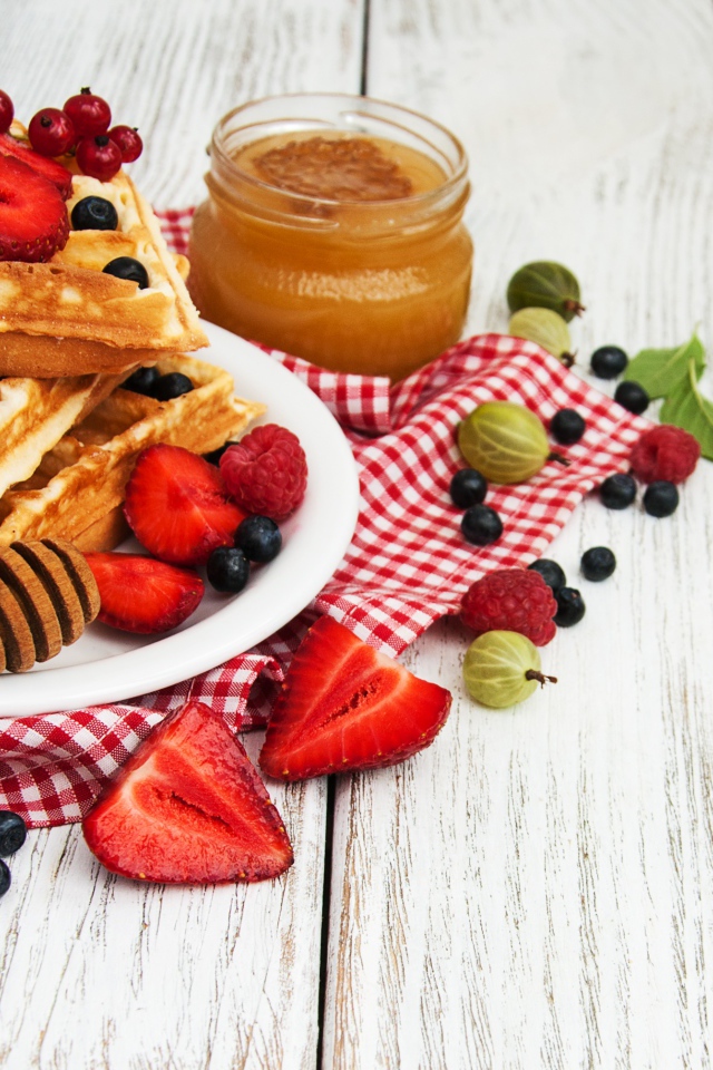 Сладкие вафли на столе с ягодами и медом