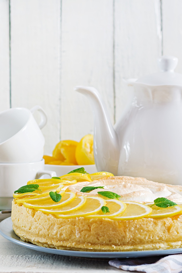 Вкусный песочный пирог с лимоном на столе с чашками и чайником