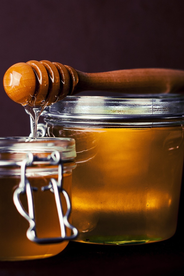 Две баночки свежего меда с деревянной ложкой