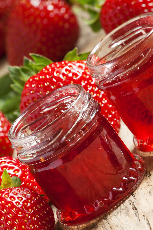 Две баночки клубничного джема на столе с клубникой