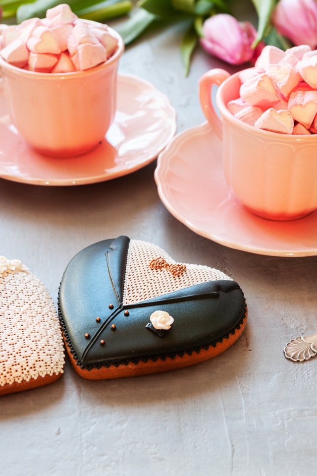 Две розовые чашки с маршмеллоу на сером фоне с печеньем и тюльпанами