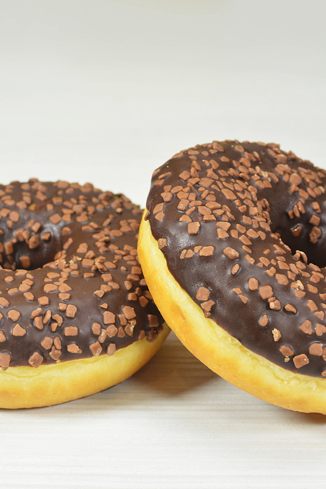 Два сладких пончика с шоколадом на сером фоне