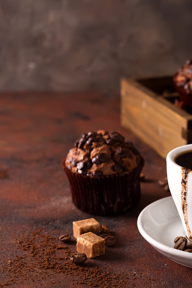 Белая чашка кофе и кекс с шоколадом на столе