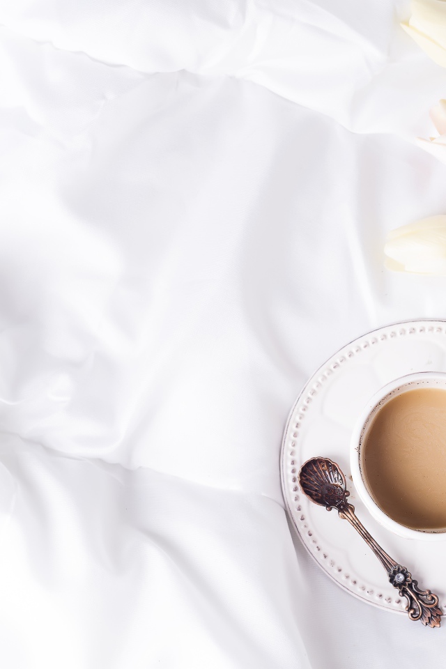 Чашка кофе на белом покрывале с тюльпанами