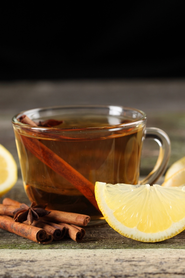 Чашка чая на столе с корицей и кусочками лимона 