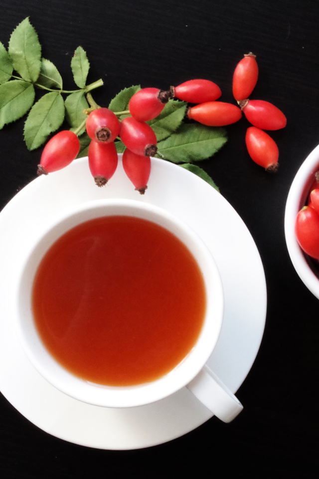 Чашка чая на столе с ягодами шиповника