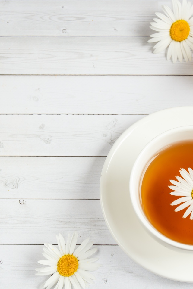 Чашка чая с ромашкой на столе с медом