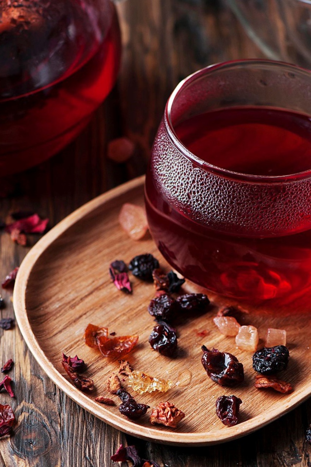 Стеклянная чашка горячего красного чая с сухофруктами 