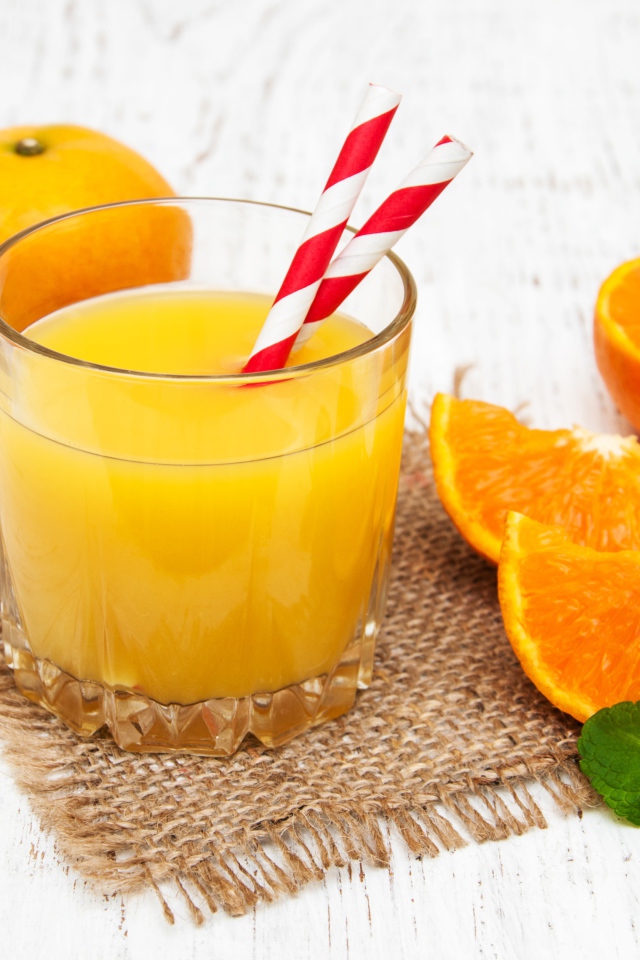 Стакан свежего сока на столе с апельсинами