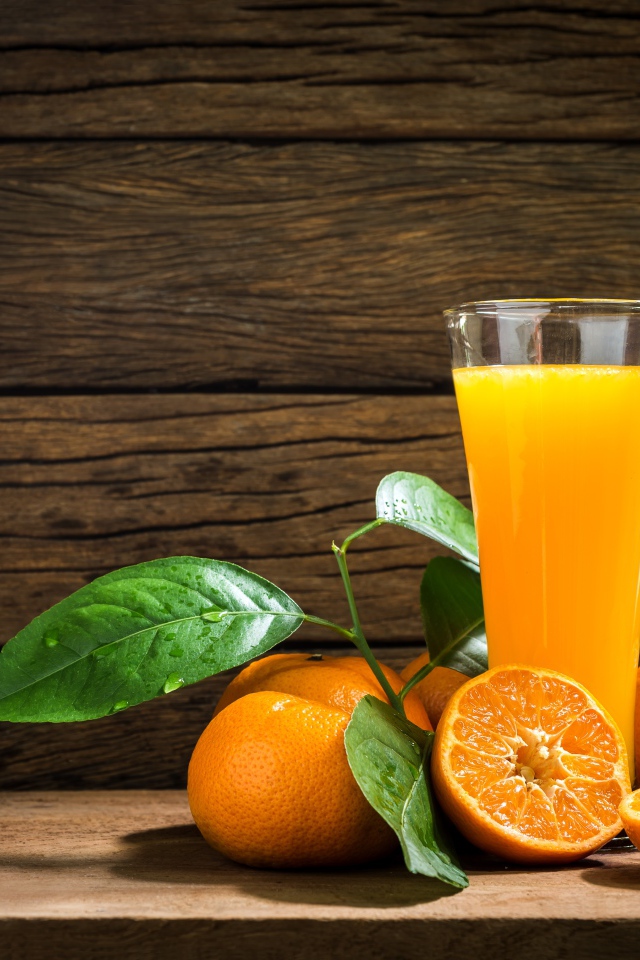 Стакан апельсинового сока на столе с мандаринами