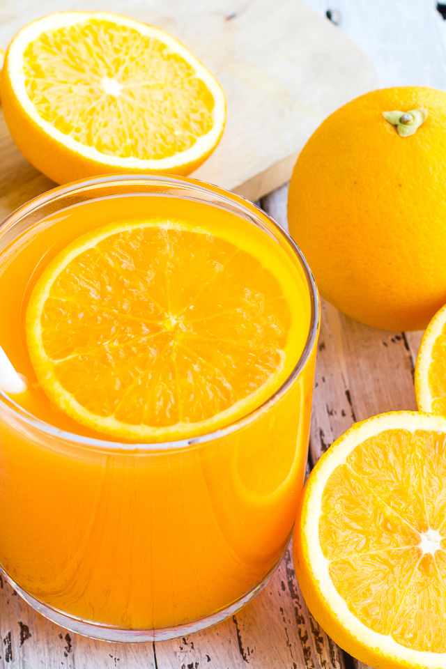 Стакан апельсинового сока на столе со свежими апельсинами на столе