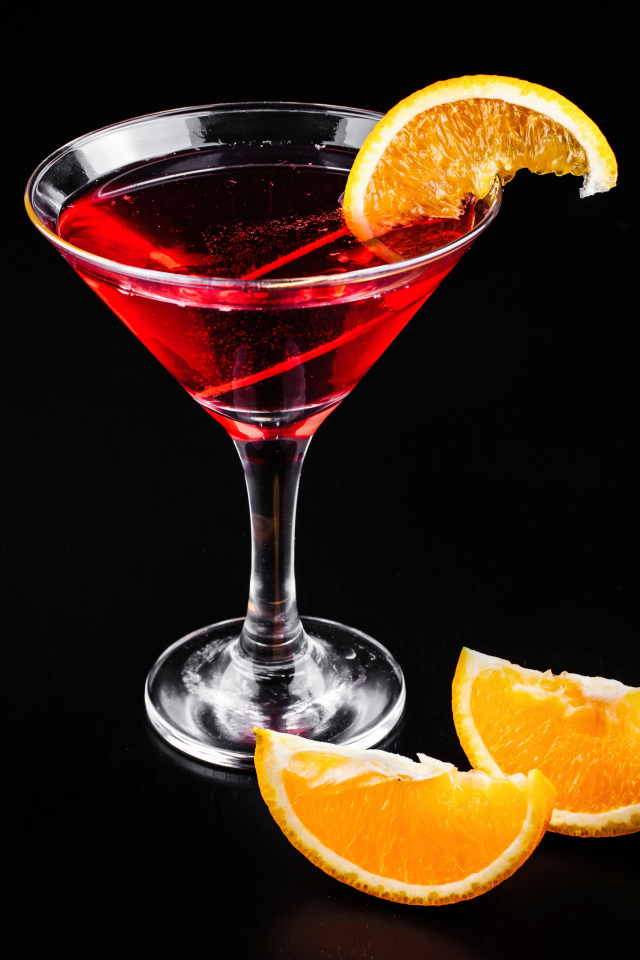 Алкогольный коктейль с кусочками апельсина на черном фоне