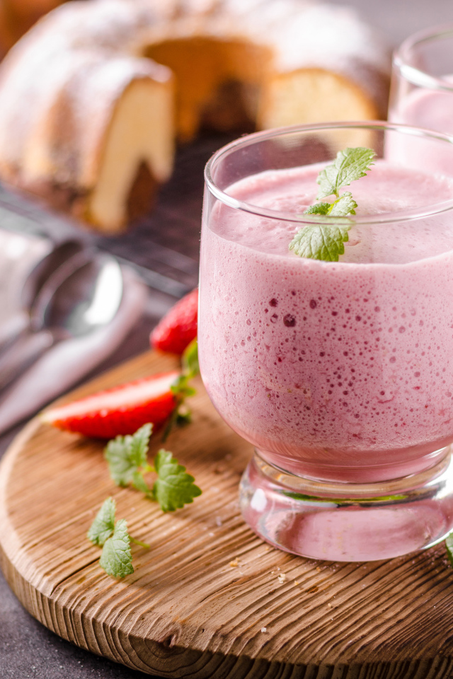 Ягодное смузи в стаканах на столе с клубникой