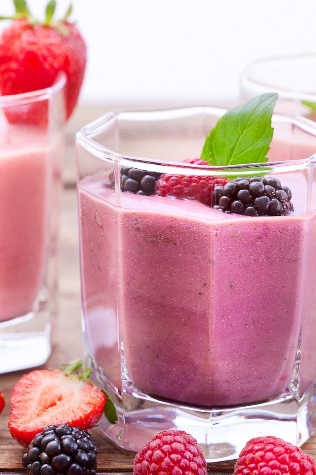 Ягодное смузи в стаканах на столе с ягодами малины, черники и клубники