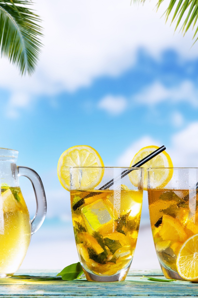 Графин и два стакана лимонада на столе на тропическом пляже