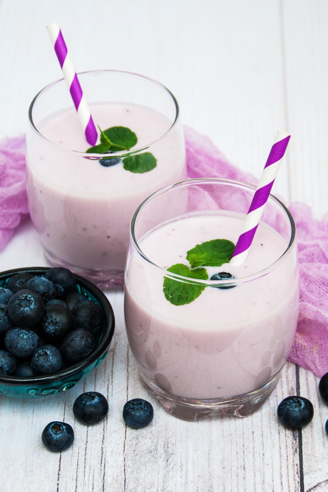 Коктейль в стаканах на столе с ягодами черники